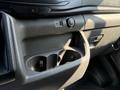 Interior dashboard area of a 2022 Ford Transit featuring cup holders a power button and a small storage compartment