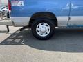 A blue 2005 Ford Econoline with a silver side panel and a white wheel tire on a black treaded tire
