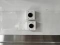 Two electrical outlets mounted on a white wall, one circular and one rectangular, with visible screws holding them in place