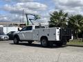 A white 2021 RAM 5500 pickup truck with a utility bed and toolboxes on the side parked in a lot