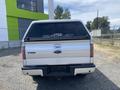 A white 2014 Ford F-150 pickup truck viewed from the rear with a Leer cap on the bed and the Ford logo visible on the tailgate