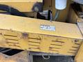 A close-up view of the lower section of a yellow 2015 Vermeer Corporation BC1200XL wood chipper showing mechanical components and a warning label