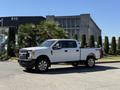 A white 2017 Ford F-350 SD pickup truck parked on a street with large wheels and extended cab
