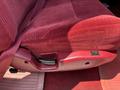 Close-up of a red fabric seat in a 1995 Ford F-250 showing the seat adjustment lever and buckle detail
