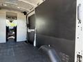 A 2022 Ford Transit van interior featuring a spacious cargo area with a black partition wall and textured flooring