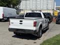 A white 2014 Ford F-150 pickup truck with a standard bed and chrome accents parked with its rear facing the viewer