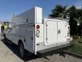 A white 2012 Ford F-350 Super Duty truck with a utility service body and various lights on the rear and sides