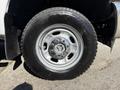 A close-up view of a 2012 Ford F-350 SD tire featuring a silver wheel with five chrome lug nuts and a rugged black tire tread pattern