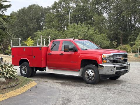A red 2015 Chevrolet Silverado 3500HD truck with a utility bed featuring storage compartments and a sturdy body designed for heavy-duty tasks