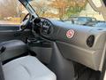 Interior view of a 2007 Ford Econoline featuring a dashboard with controls and a cup holder area along with a gray upholstery seat