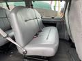 A side view of the interior of a 2010 Ford Econoline showing a gray bench seat with seatbelts and a seat back without headrests