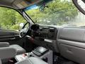 Interior of a 2007 Ford F-550 featuring gray seats a dashboard with controls and a radio, and a central console with equipment and a manual laying on it