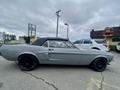 A 1968 Ford Mustang Two Door Convertible in gray with a black convertible top and black wheels viewed from the side