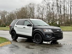 A 2019 Ford Explorer featuring a black and white color scheme with black wheels and a sleek design parked on a wet surface