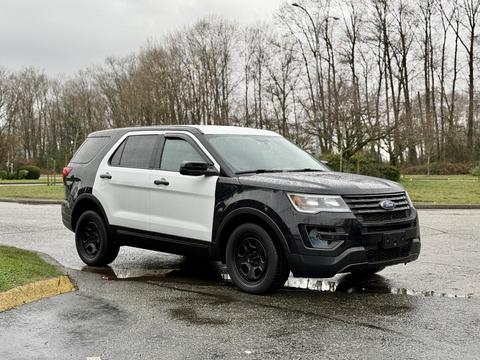 A 2019 Ford Explorer featuring a black and white color scheme with black wheels and a sleek design parked on a wet surface