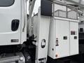 A white 2013 Freightliner 114SD truck with a side-mounted compartment and safety labels on its door