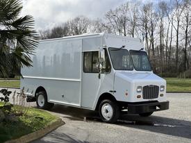 A white 2017 Freightliner MT45 delivery truck with a boxy shape and large front windows parked with its side facing the viewer