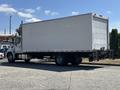A 2020 Hino 338 truck with a large empty cargo box and a liftgate at the rear parked on a driveway