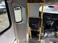 Interior view of a 2018 Chevrolet Express showing a driver's seat and control panel with a yellow support pole and a black storage bag attached to the wall
