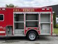 2007 Ford F-550 fire and rescue truck with red exterior featuring open storage compartments on the side and the words FIRE RESCUE displayed prominently