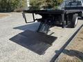 A 2018 Ford F-750 truck with a flatbed and a hydraulic lift gate at the rear positioned on a gravel surface