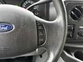 Close-up of a steering wheel with buttons for cruise control on a 2017 Ford E450 featuring the Ford logo on the wheel