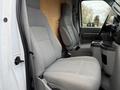 A 2019 Ford Econoline van interior featuring two gray cloth front seats and a central console with cup holders