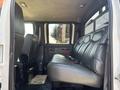 Interior view of a 2005 GMC C7500 Topkick featuring a large bench seat with leather upholstery and a backrest along with two individual seats in the foreground