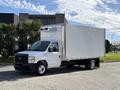 A 2023 Ford E-450 box truck with a white cargo area and a front cab in black and white parked on the street