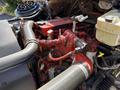 Close-up of a 2011 Freightliner B2 engine showing red and black components with visible wires and hoses together with a coolant reservoir
