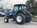 A blue and black 2009 New Holland T4020 tractor with large rear tires and a cabin featuring glass windows