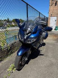 A 2016 Yamaha FJR1300AE motorcycle in blue with a fairing and saddlebags parked on a paved surface