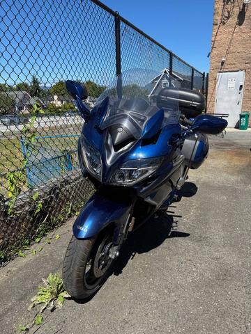 A 2016 Yamaha FJR1300AE motorcycle in blue with a fairing and saddlebags parked on a paved surface