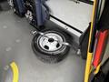 A spare tire with a silver rim lies on the floor of a vehicle