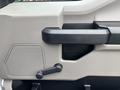 Interior door handle and controls of a 2020 Ford F-150 with a textured surface and a speaker grille below the handle
