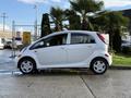 A 2012 Mitsubishi I-MiEV parked sideways with a compact design shiny white exterior and distinctive round headlights