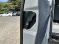 A 2016 Ford Transit 150 van with a close-up view of its door latch mechanism showcasing a black handle and silver screw