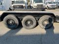 A 2020 Load Trail 28 Foot Gooseneck trailer with three large black wheels and a flatbed design set on a paved surface