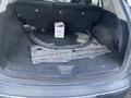 The cargo area of a 2017 Nissan Murano featuring an empty space with a cardboard box and various car parts including a metal piece and a curved item