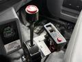 The interior control panel of a 2017 Ford F-750 featuring a gear shift lever with a red knob and a digital display with various buttons and a warning label