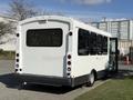 A 2017 Chevrolet Express bus with a white exterior and large rear windows parked with its door open