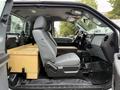 Interior view of a 2015 Ford F-350 SD with gray cloth seats and a wooden storage box on the passenger side