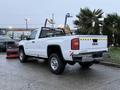 A 2017 GMC Sierra 3500HD pickup truck with a white exterior and a rear grille guard is parked on a concrete surface