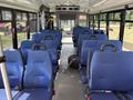 Interior of a 2020 Chevrolet Express with multiple blue seats arranged in rows facing forward and a wide aisle in the center