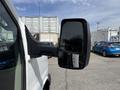 A side mirror of a 2017 Chevrolet Express van reflecting a parked vehicle and nearby palm trees