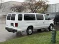 A white 2013 Ford E-350 van parked on the street with its rear doors closed and steam rising from the ground around it