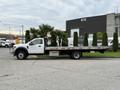 A 2022 Ford F600 truck with a flatbed is parked, featuring a white exterior and a streamlined design, ideal for transporting heavy loads