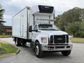 A 2019 Ford F-750 truck with a white box cargo trailer parked in a driveway facing forward with a cooling unit on top
