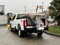A 2023 Ford F-250 pickup truck with a salt spreader attached to its bed and a snow plow in front