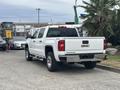 A white 2016 GMC Sierra 1500 pickup truck parked with a chrome rear bumper and the GMC logo displayed on the tailgate